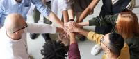 A team joins hands at a team meeting.